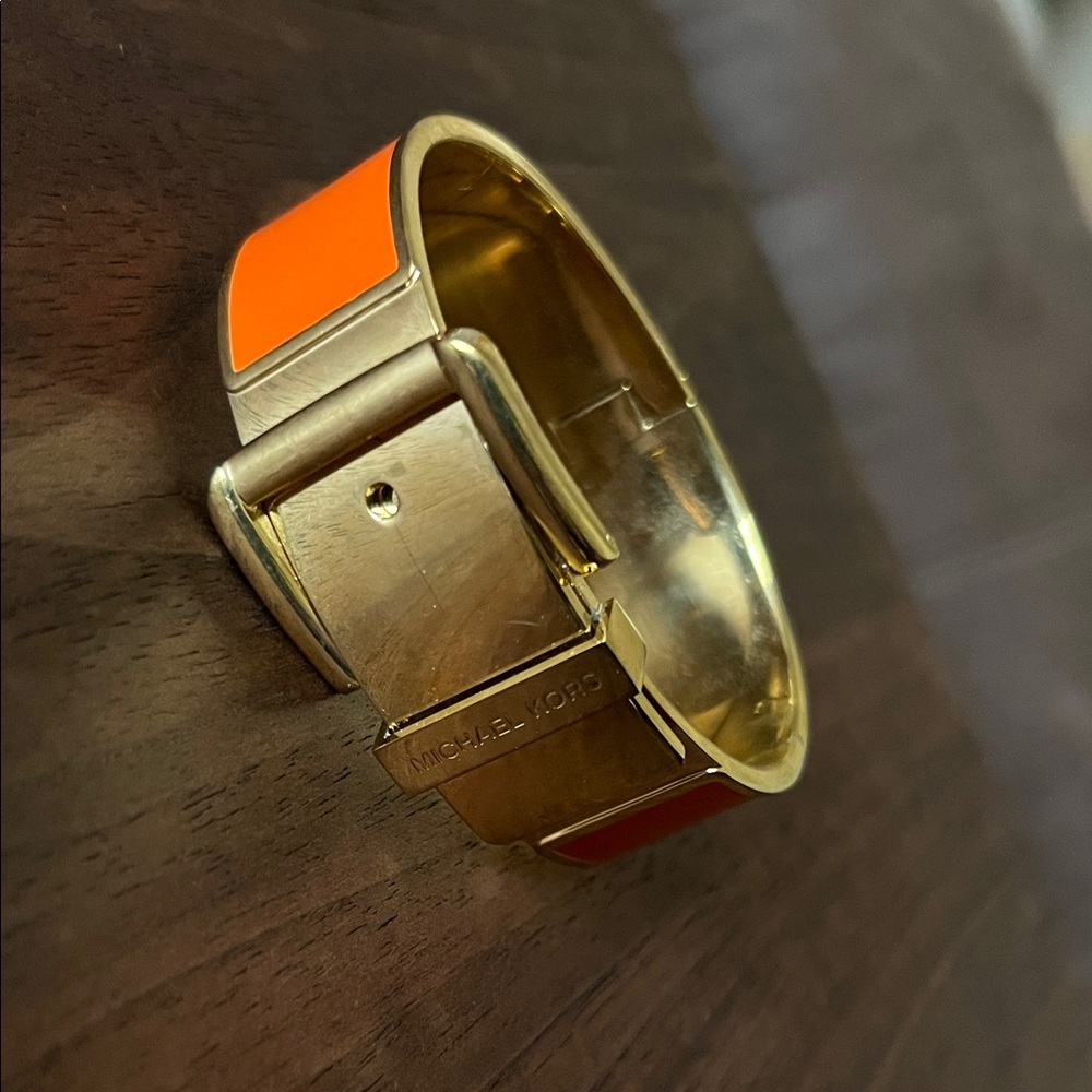 Michael Kors gold-tone and orange enamel hinged buckle bangle bracelet.